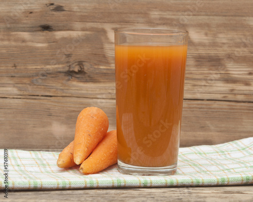 Photo: Glass of carrot juice and ripe carrots on colorful napkin Glass of carrot juice and ripe carrots on colorful napkin