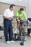 Photo: Sports scientist with digital tablet monitoring cyclist on exercise bike in laboratory Sports scientist with digital tablet monitoring cyclist on exercise bike in laboratory