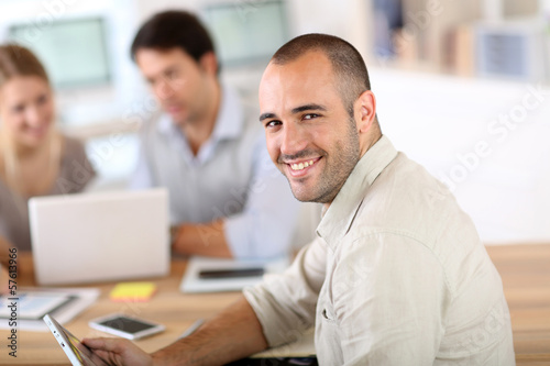 Photo: Young man in office working on digital tablet Young man in office working on digital tablet
