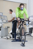 Photo: Sports scientist at computer and cyclist with mask on exercise bike in laboratory Sports scientist at computer and cyclist with mask on exercise bike in laboratory