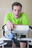 Photo: Portrait of serious runner holding mask and leaning on treadmill in sports science laboratory Portrait of serious runner holding mask and leaning on treadmill in sports science laboratory