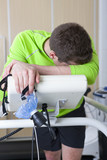 Photo: Tired runner with head in hands holding mask and leaning on treadmill in sports science laboratory Tired runner with head in hands holding mask and leaning on treadmill in sports science laboratory