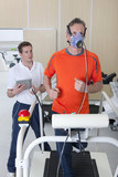 Foto: Sports scientist with digital tablet monitoring runner with mask on treadmill in laboratory Sports scientist with digital tablet monitoring runner with mask on treadmill in laboratory
