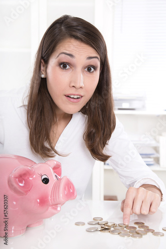 Photo: Junge Frau im Büro mit Sparschwein und Geld - Konzept Junge Frau im Büro mit Sparschwein und Geld - Konzept