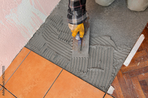 Photo: Home renovation worker trowel spreading mortar for ceramic tile Home renovation worker trowel spreading mortar for ceramic tile