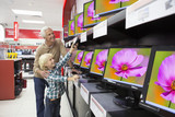 Foto : Grandfather and grandson holding remote control and looking up at televisions in electronics store Grandfather and grandson holding remote control and looking up at televisions in electronics store