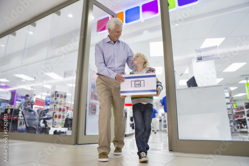Photo: Grandfather and grandson leaving electronics store with boxed speakers Grandfather and grandson leaving electronics store with boxed speakers
