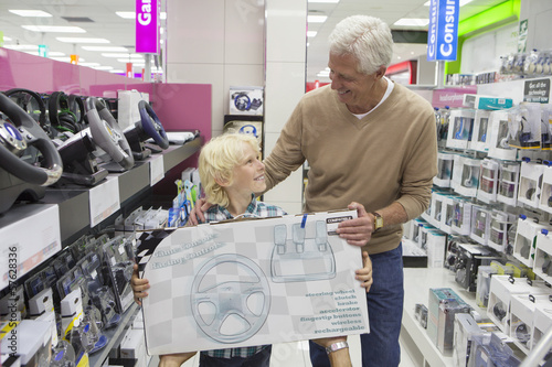Photo: Smiling grandfather and grandson holding video game box in electronics store Smiling grandfather and grandson holding video game box in electronics store