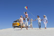 Photo: Happy multi-generation family walking with kite on sunny beach with van in background Happy multi-generation family walking with kite on sunny beach with van in background