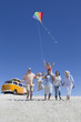 Photo: Happy multi-generation family with kite walking on sunny beach with van in background Happy multi-generation family with kite walking on sunny beach with van in background