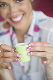 Photo : Close up portrait of woman holding tiny cup with flower design on manicured fingernails Close up portrait of woman holding tiny cup with flower design on manicured fingernails