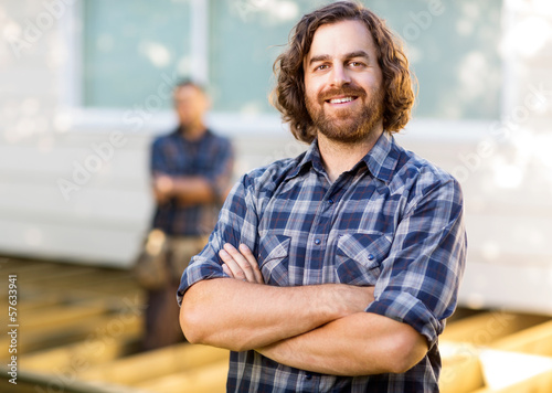 Photo: Carpenter With Arms Crossed Standing At Construction Site Carpenter With Arms Crossed Standing At Construction Site