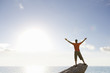 Photo: Male rock climber standing with arms outstretched on top of rock overlooking ocean Male rock climber standing with arms outstretched on top of rock overlooking ocean