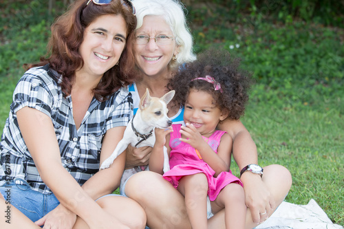 Photo: Hispanic family with a small dog sitting on the grass Hispanic family with a small dog sitting on the grass