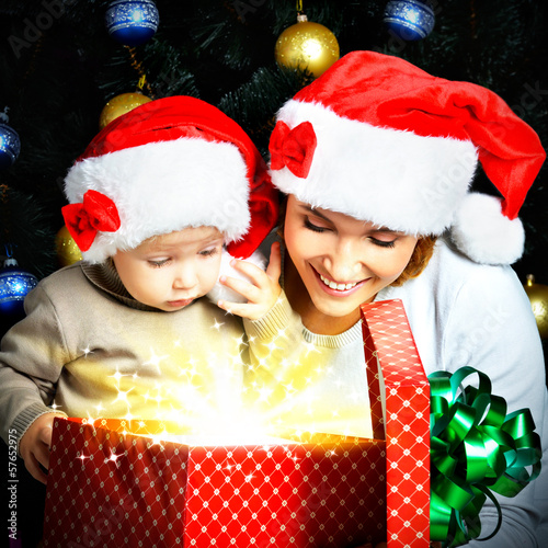 Photo: Mother with little child opens the box with gifts on christmas Mother with little child opens the box with gifts on christmas