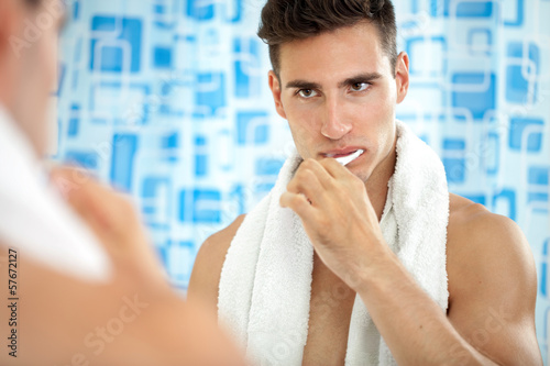 Photo: Man brushing teeth in front of mirror Man brushing teeth in front of mirror