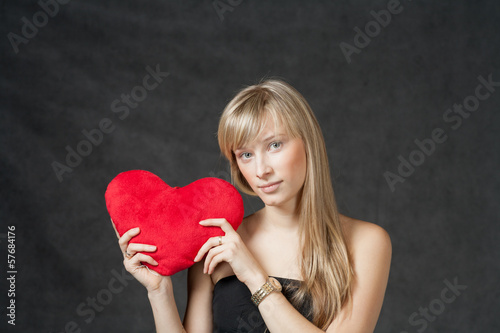 Photo: American Blond haired Woman with a Heart-Shaped Cushion on dark American Blond haired Woman with a Heart-Shaped Cushion on dark