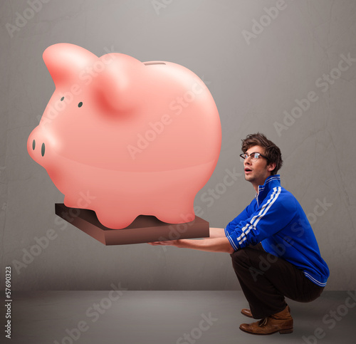 Photo: Handsome man holding a huge savings piggy bank Handsome man holding a huge savings piggy bank