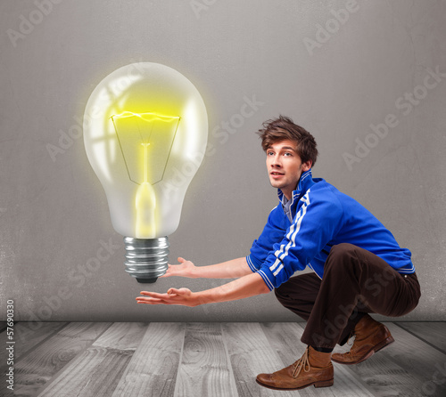 Photo: Attractive man holding realistic 3d light bulb Attractive man holding realistic 3d light bulb