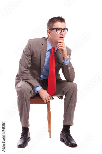 Photo: seated young business man looks away pensively seated young business man looks away pensively