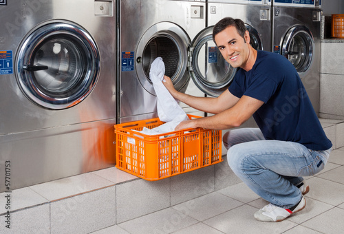 Photo: Young Man Putting Clothes In Washing Machine Young Man Putting Clothes In Washing Machine