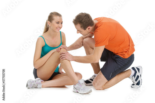 Photo: Handsome trainer checking woman knee. Handsome trainer checking woman knee.