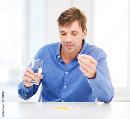 Photo: ill man taking his pills at home ill man taking his pills at home