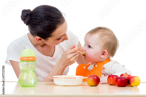 Photo: young mother spoon feeding her baby girl young mother spoon feeding her baby girl