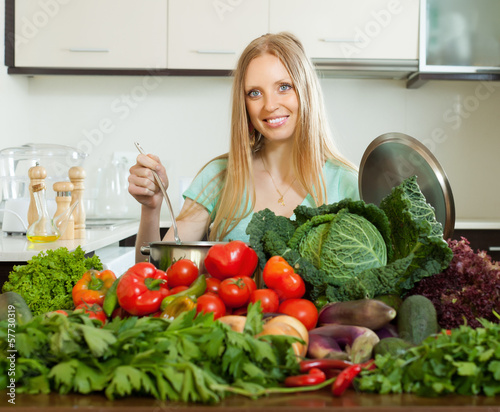 Photo: happy woman cooking with heap of raw vegetables happy woman cooking with heap of raw vegetables