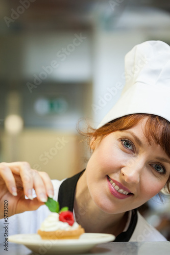 Photo: Smiling head chef putting mint leaf on little cake Smiling head chef putting mint leaf on little cake