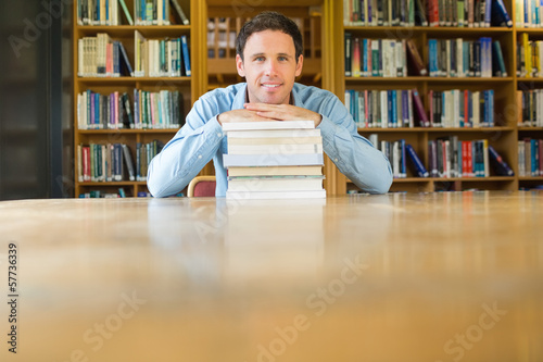 Photo: Smiling mature student with stack of books at library desk Smiling mature student with stack of books at library desk