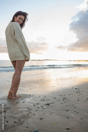 Photo: Full length of a woman in sweater standing on beach Full length of a woman in sweater standing on beach