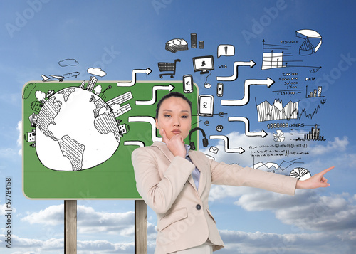 Photo: Composite image of thoughtful asian businesswoman pointing Composite image of thoughtful asian businesswoman pointing