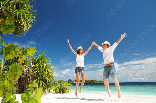 Photo: Happy couple jumping on the tropical beach Happy couple jumping on the tropical beach