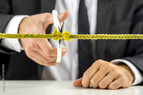 Photo: Businessman cutting yellow rope Businessman cutting yellow rope