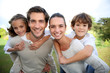 Parents giving piggyback ride to children