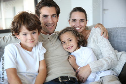 Photo: Happy family of four relaxing in sofa Happy family of four relaxing in sofa