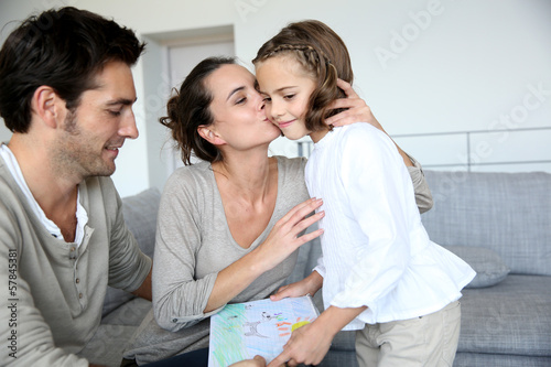 Photo: Cute little girl giving drawing to her parents Cute little girl giving drawing to her parents