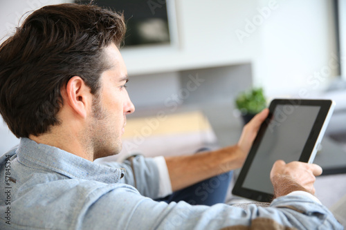 Photo: Attractive man at home using digital tablet Attractive man at home using digital tablet