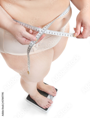 Photo: Overweight woman measuring her waist belly by metre-stick. Overweight woman measuring her waist belly by metre-stick.