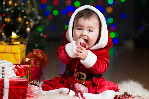 Photo: kid girl dressed as Santa Claus at Christmas tree with gifts kid girl dressed as Santa Claus at Christmas tree with gifts