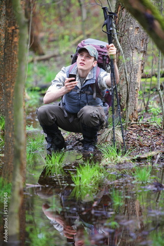 Photo: lost hiker in forest with mobile satelite navigation device lost hiker in forest with mobile satelite navigation device