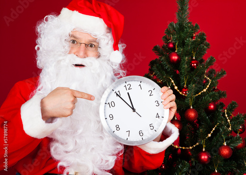 Photo: Portrait of a happy santa holding clock Portrait of a happy santa holding clock