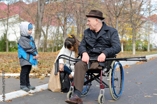 Photo: Woman and her son helping a disabled old man Woman and her son helping a disabled old man
