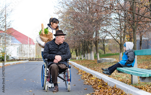 Photo: Disabled man and his carer chat to a little boy Disabled man and his carer chat to a little boy