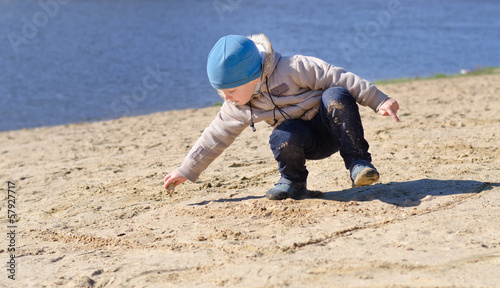 Photo: Cute little boy playing on a sandy beach Cute little boy playing on a sandy beach