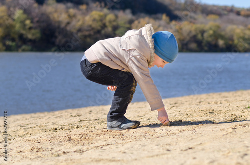 Photo: Small boy drawing in the beach sand Small boy drawing in the beach sand