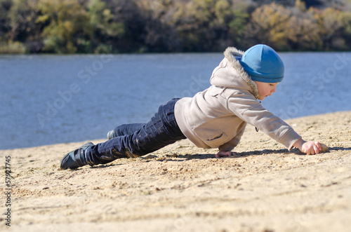 Photo: Young boy playing on beach sand at the coast Young boy playing on beach sand at the coast
