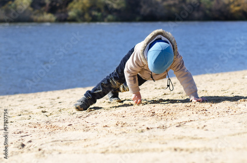 Photo: Young boy playing on beach sand at the coast Young boy playing on beach sand at the coast