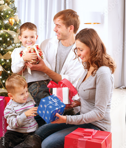 Photo: Christmas Family. Children Opening Gifts. Christmas tree Christmas Family. Children Opening Gifts. Christmas tree